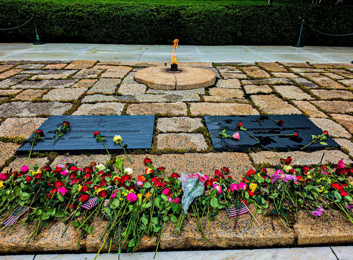 The eternal flame at the gravesite of John F. Kennedy and Jacqueline Kennedy Onassis, surrounded by roses left by visitors