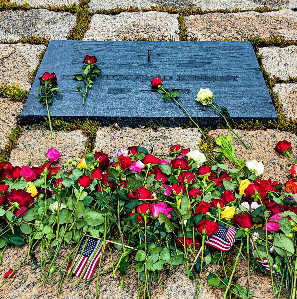 The grave marker of John F. Kennedy with roses laid across it