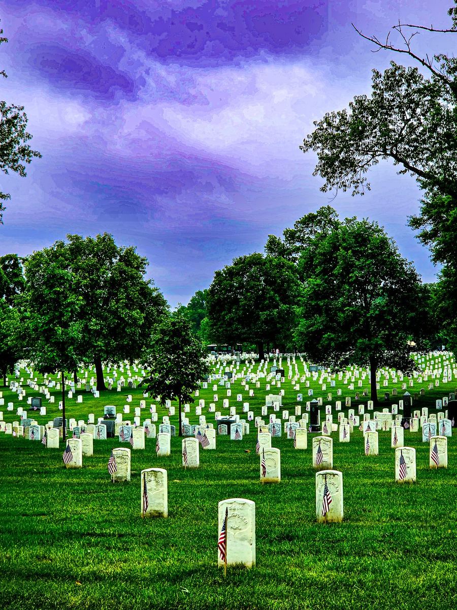Cemetery field of headstones beneath a dramatic purple sky