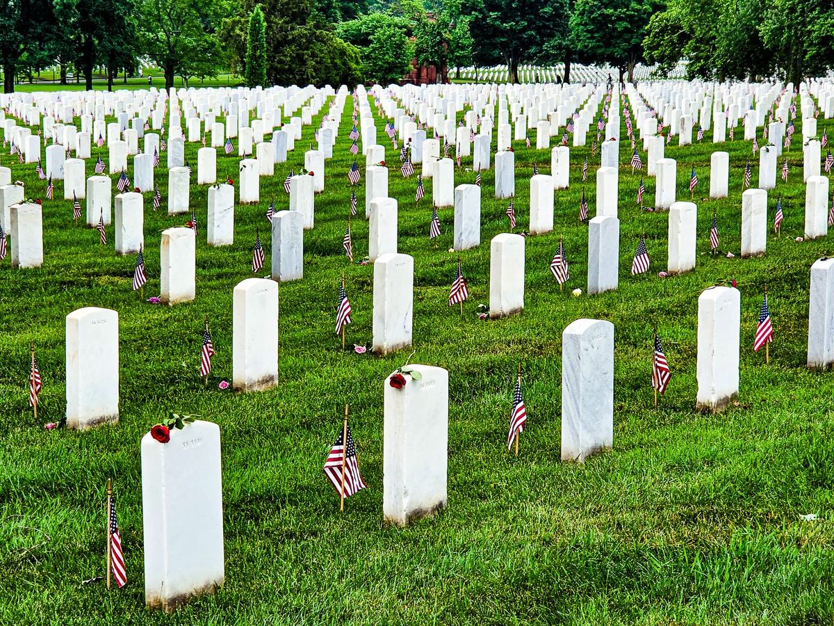 A wide expanse of white headstones at Arlington, each with an American flag
